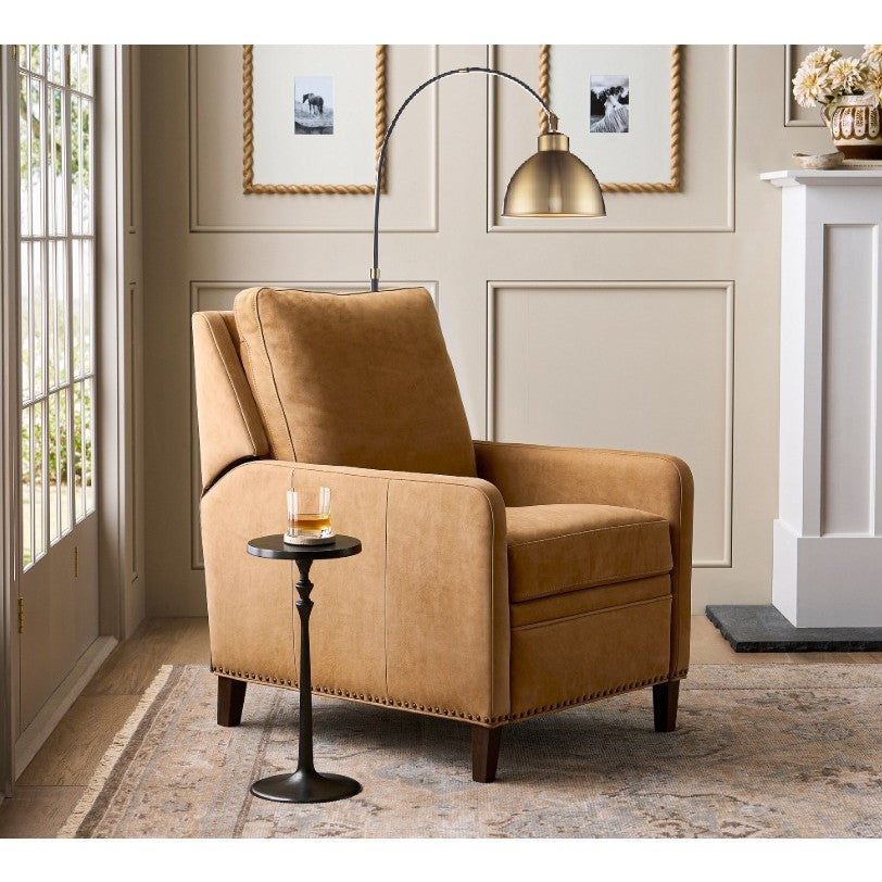 Tan leather armchair in a living room with a floor lamp and side table.