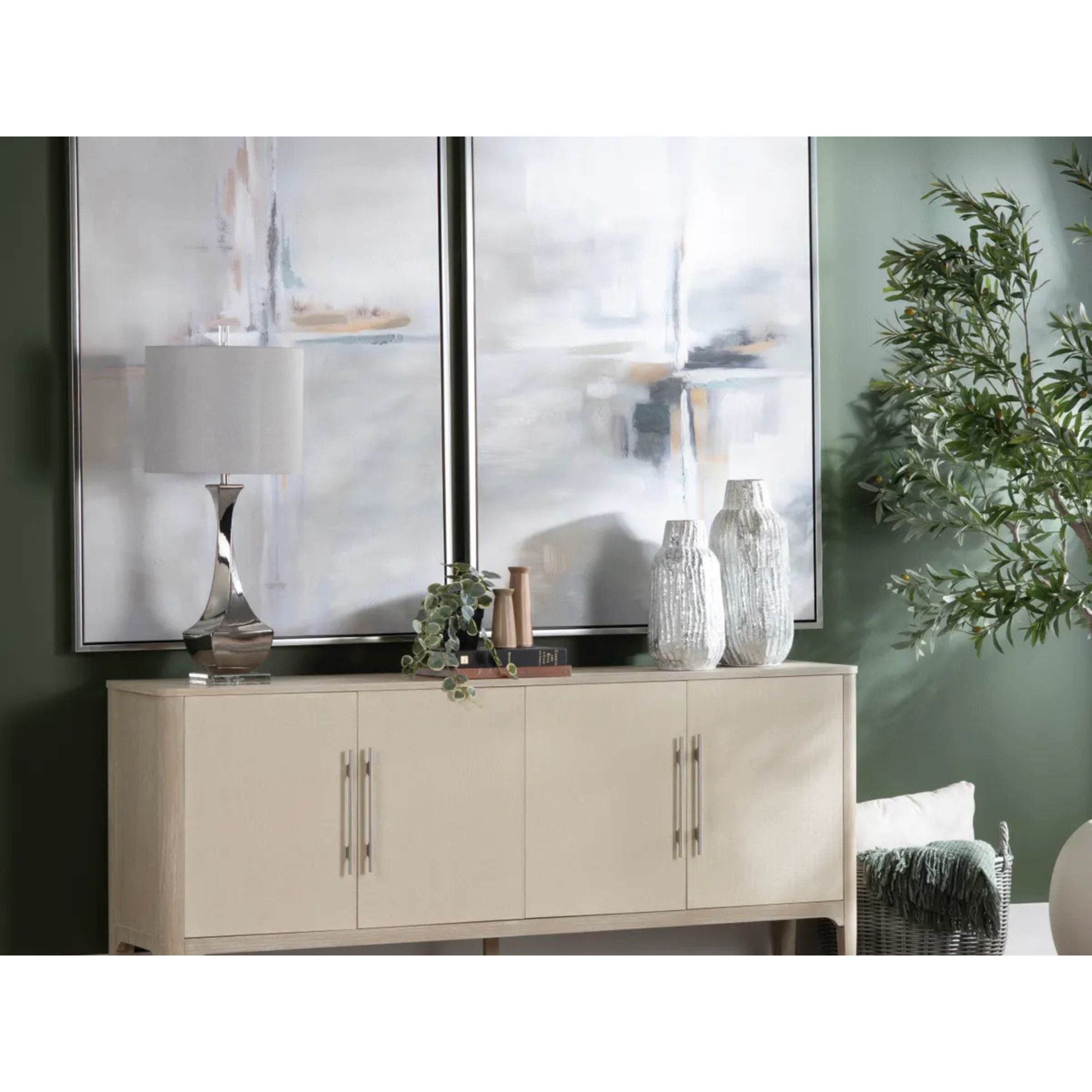 Modern console table with metallic lamp, abstract art, decor vases, and indoor plant.
