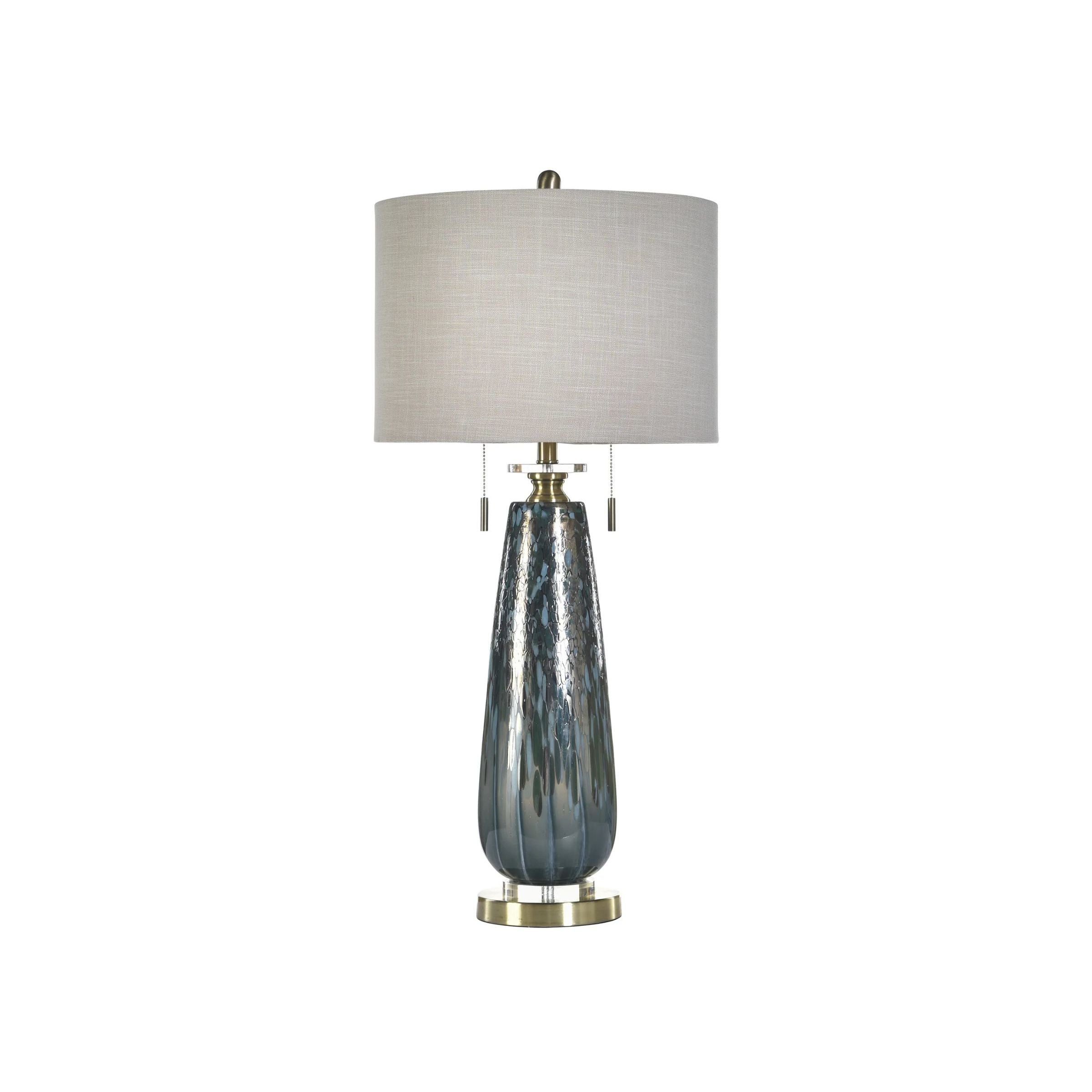 Modern table lamp with textured blue glass base and white drum shade.