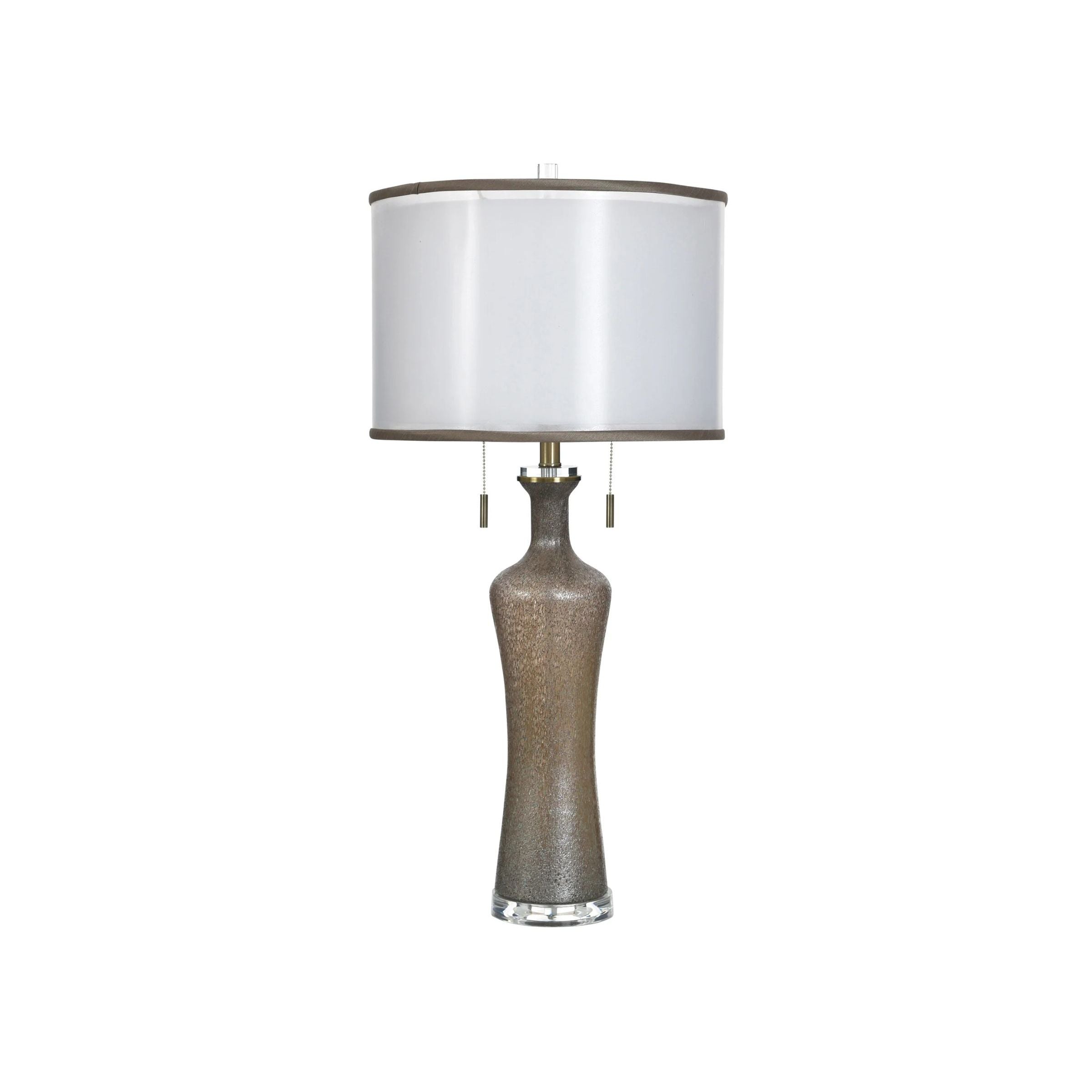 Tall metallic table lamp with a white drum shade.