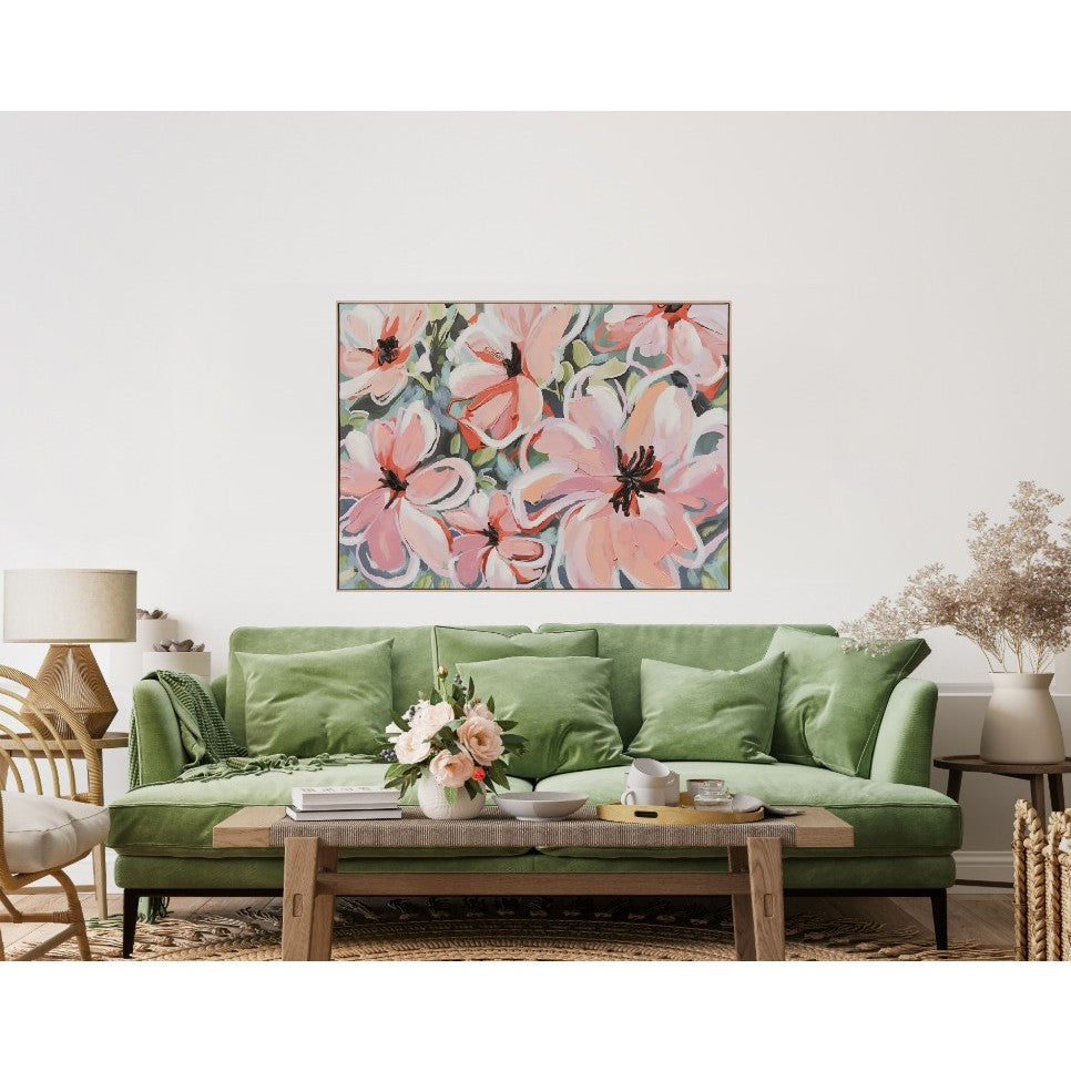 Living room with green sofa, abstract pink floral artwork, and coffee table with flower arrangement.
