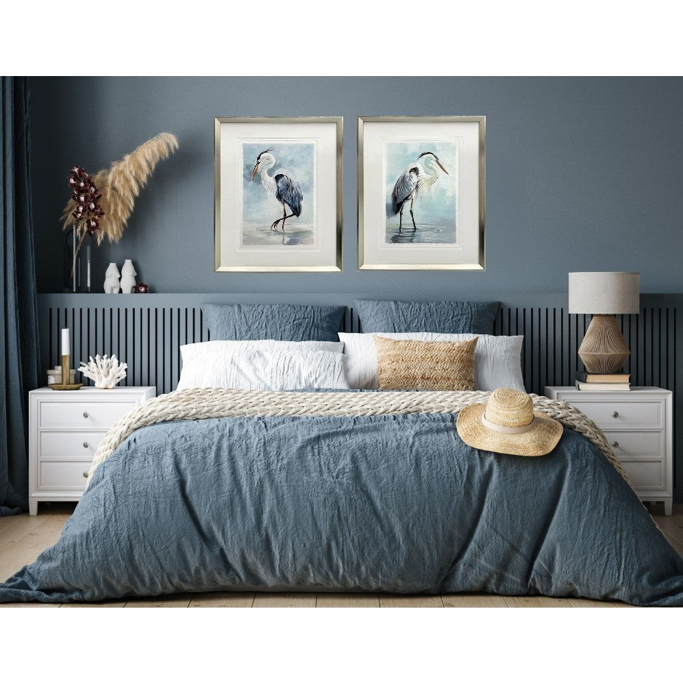 Blue bedroom with two framed heron bird prints above the bed.