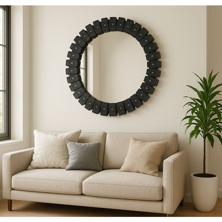 Round decorative mirror above beige sofa with neutral pillows in a modern living room.