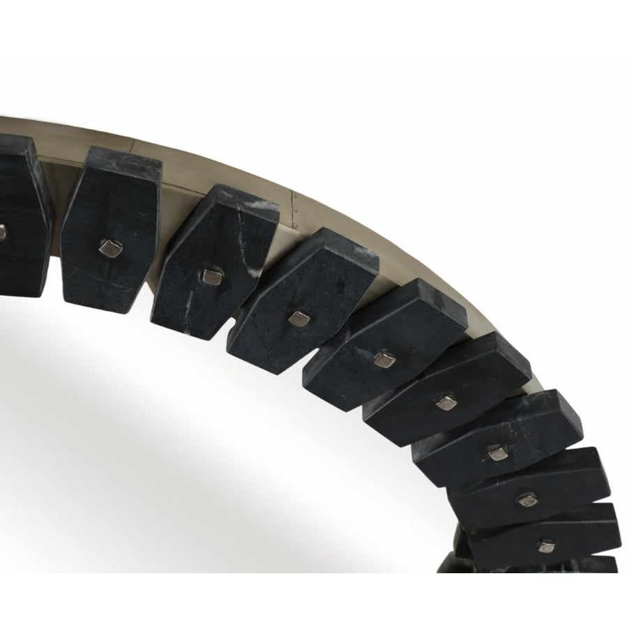 Close-up of a mirror frame with dark geometric blocks and metallic studs.