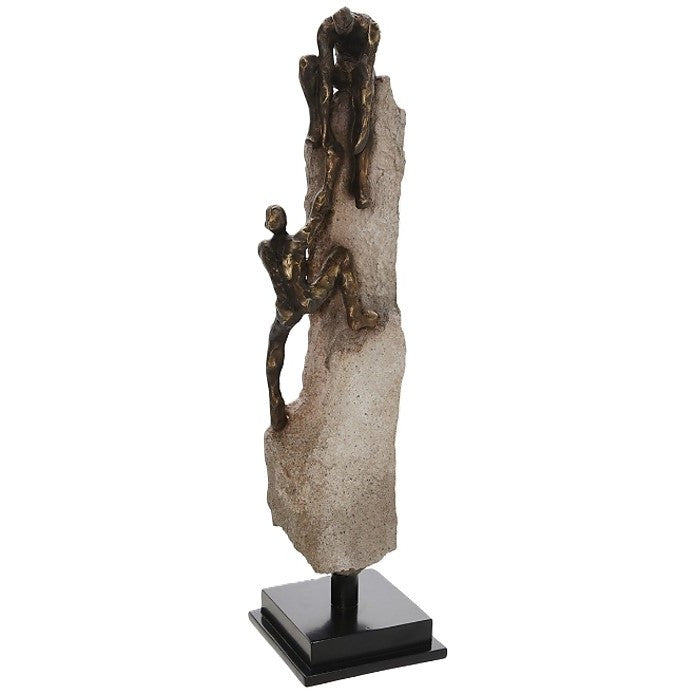 Sculpture of two figures climbing and helping each other on a stone base.