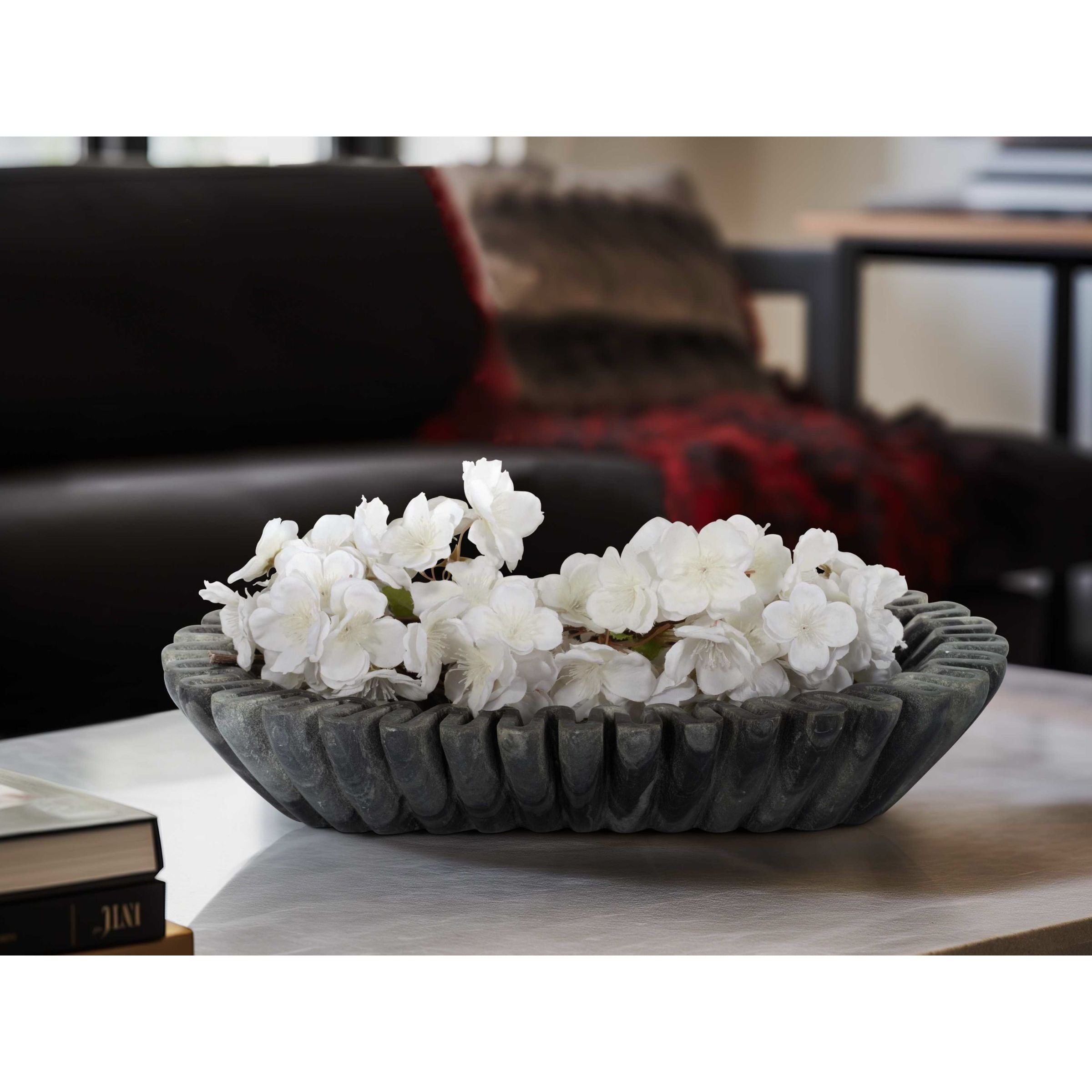 Decorative bowl with white flowers on a table in a modern living room.