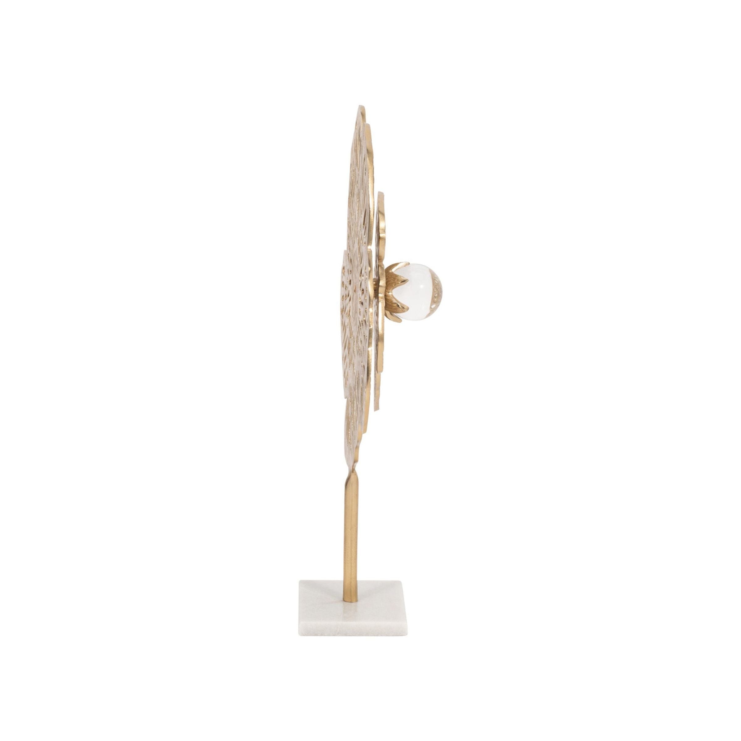Side view of a decorative gold metal sculpture on a marble base.