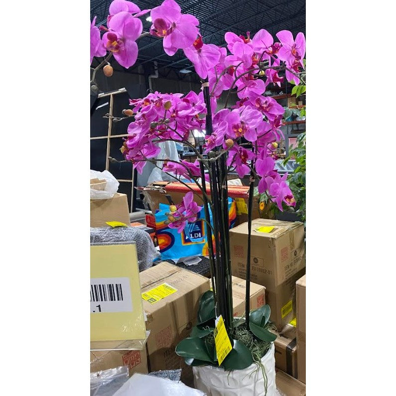 Potted artificial orchid with bright pink blooms in a warehouse setting.