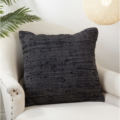 Black woven throw pillow on a white accent chair