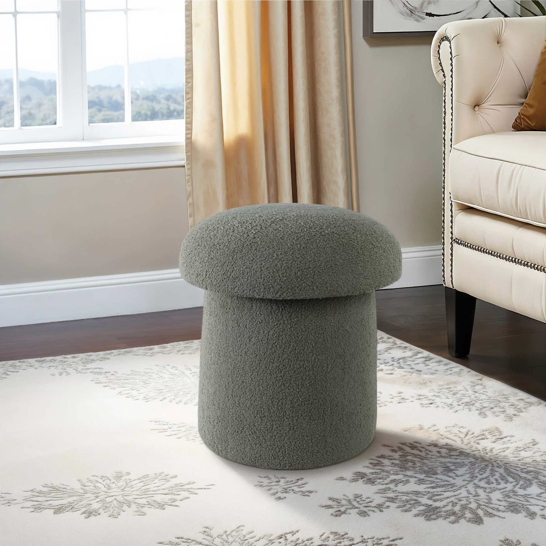 Gray textured ottoman in a living room near a window and cream-colored sofa.