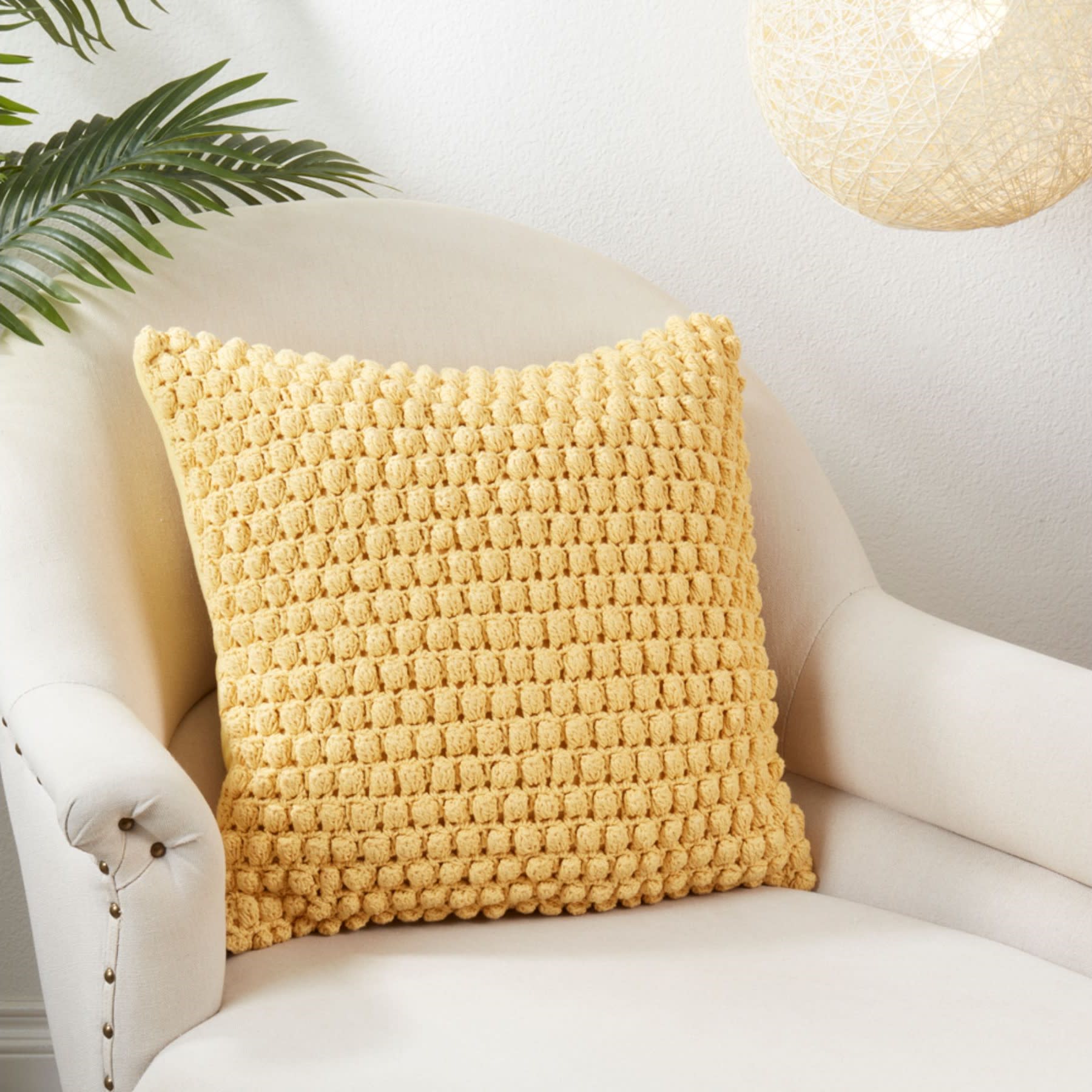 Yellow textured throw pillow on a cream armchair in a modern living room.