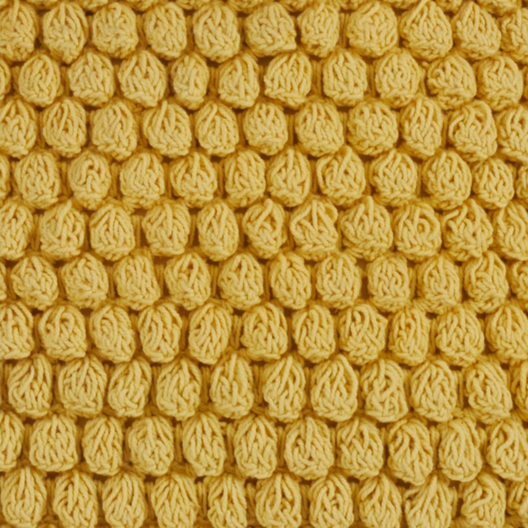Close-up of yellow textured knit fabric with a bubble or popcorn pattern.