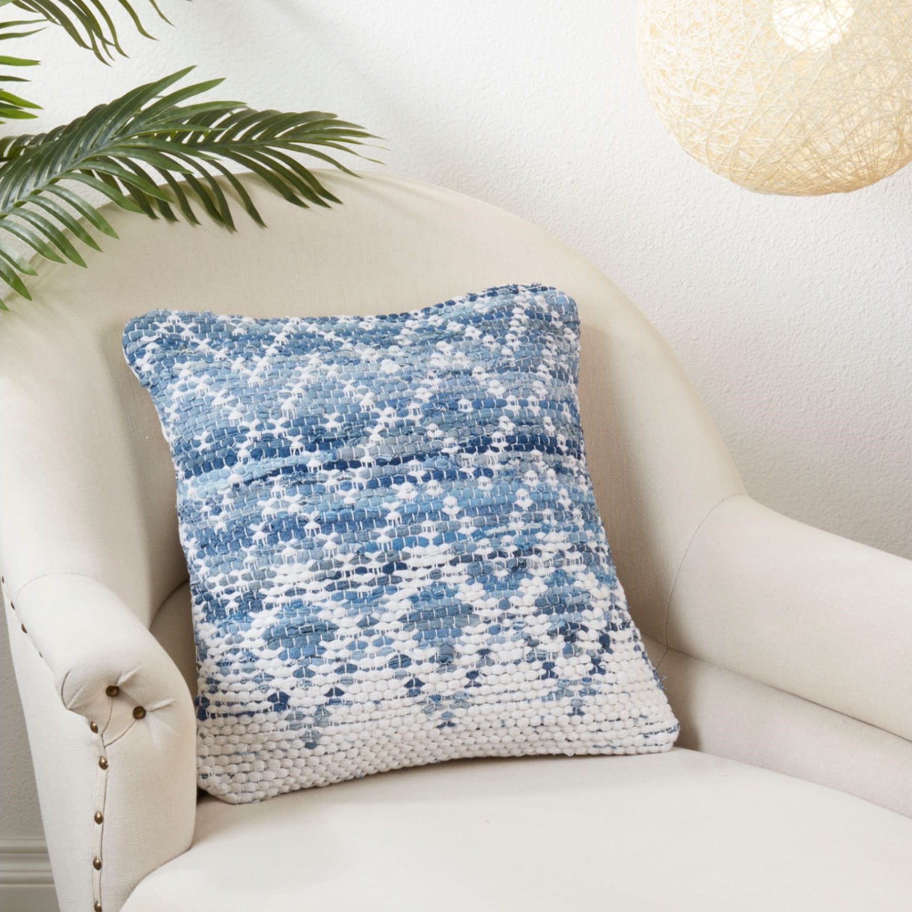 Blue and white patterned throw pillow on a cream armchair in a cozy living space.