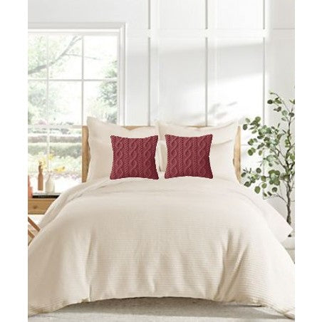 Cream bedding with two red decorative pillows in a bright, modern bedroom.