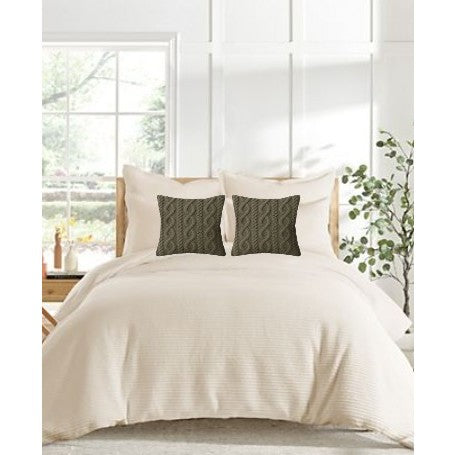 Neutral bedroom with cream bedding and two patterned dark throw pillows on a bed.