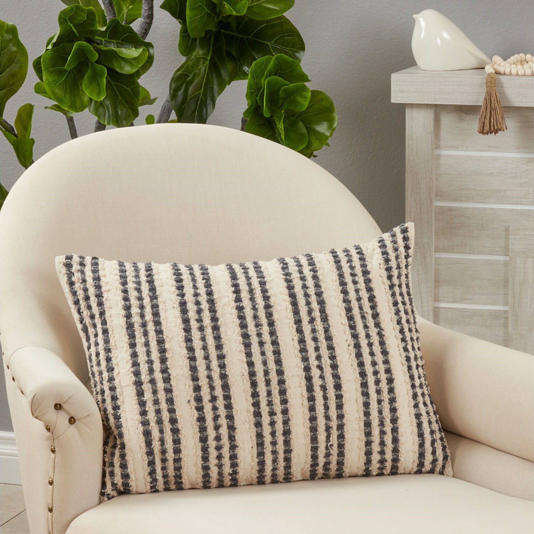 Beige armchair with a textured, striped throw pillow in a modern room setting.