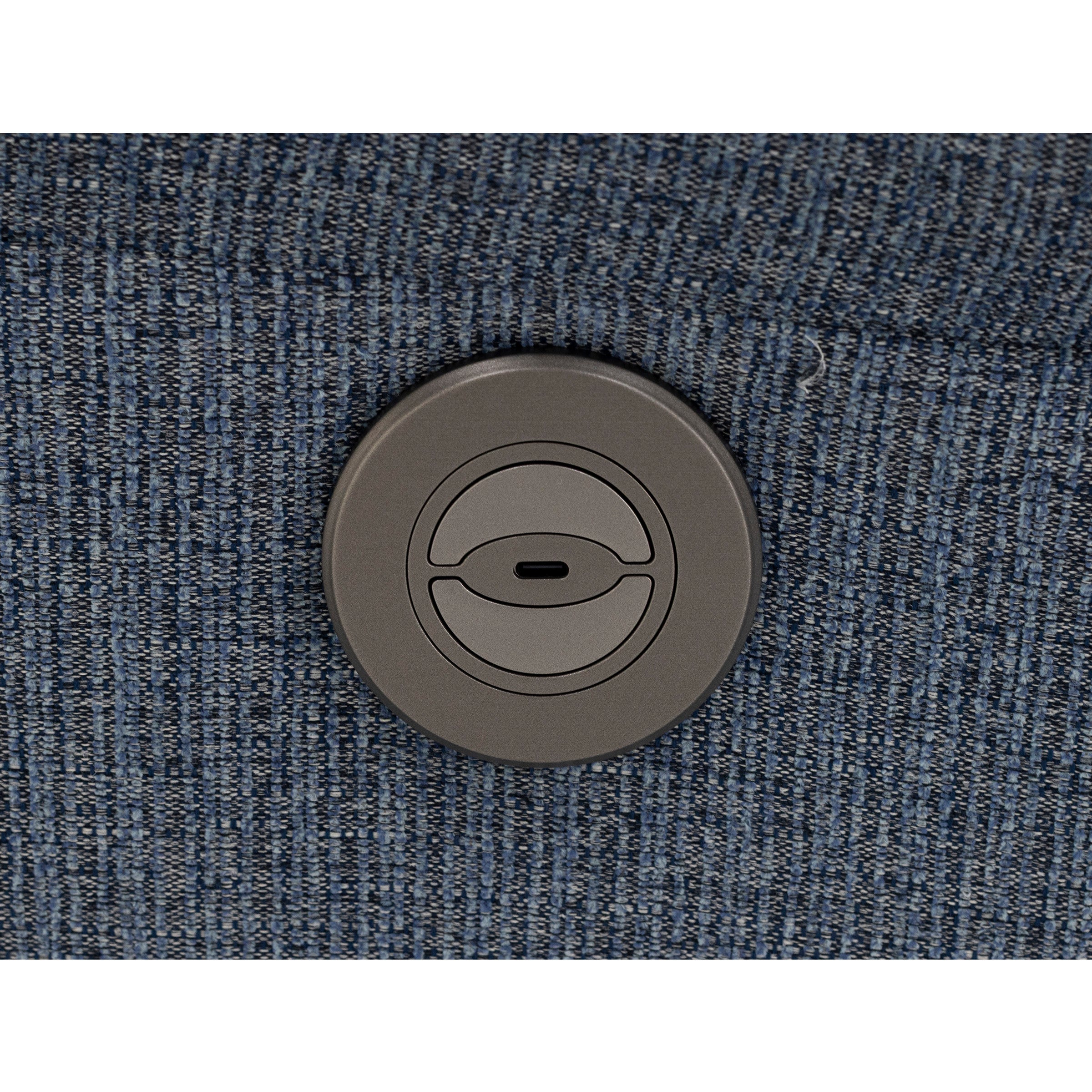 Round power button on blue upholstered fabric.