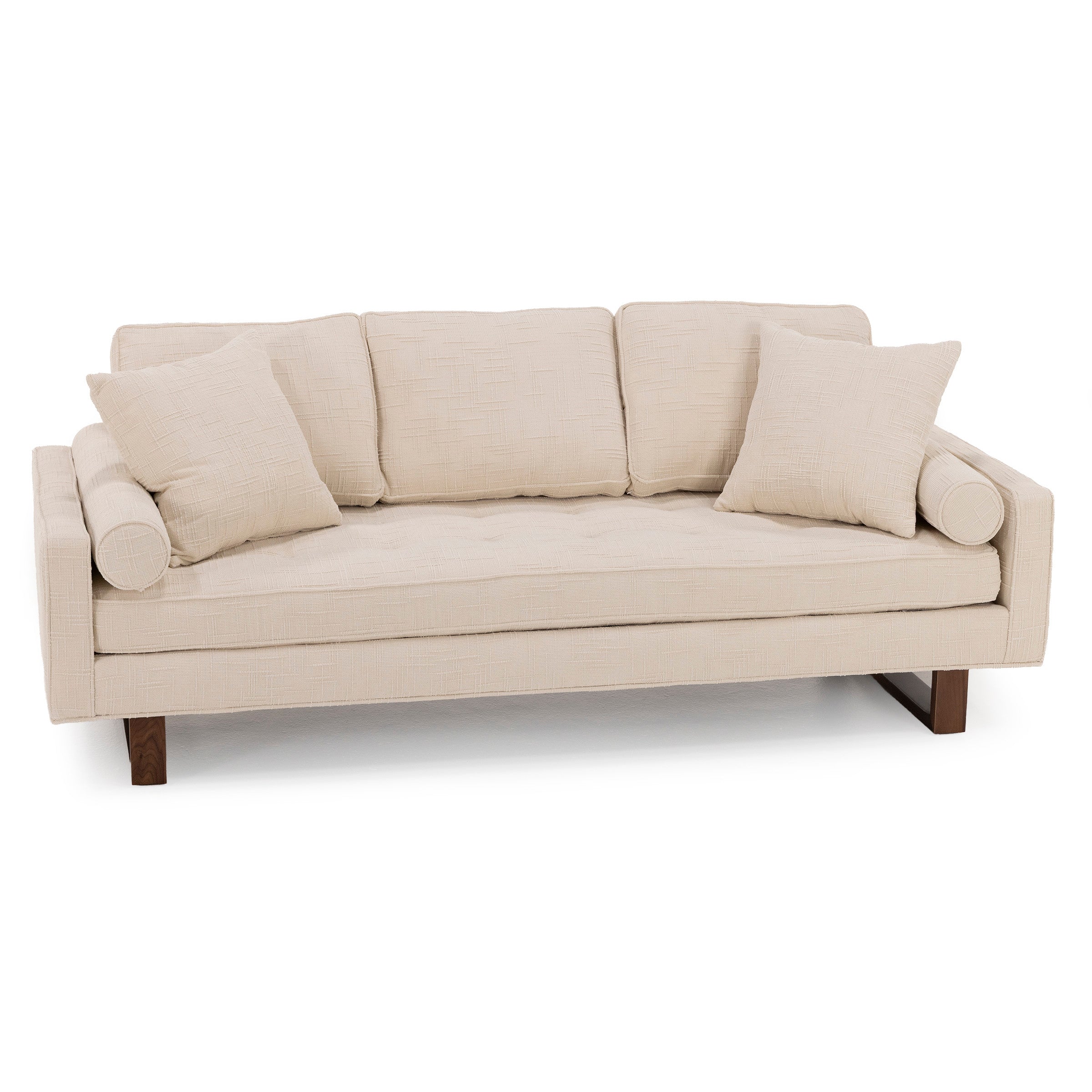 Beige modern sofa with two square and two round pillows, wooden legs, and textured upholstery.