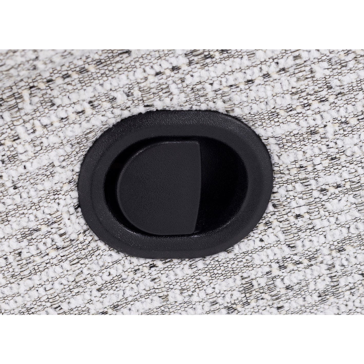 Close-up of a black oval recliner switch on textured light fabric.