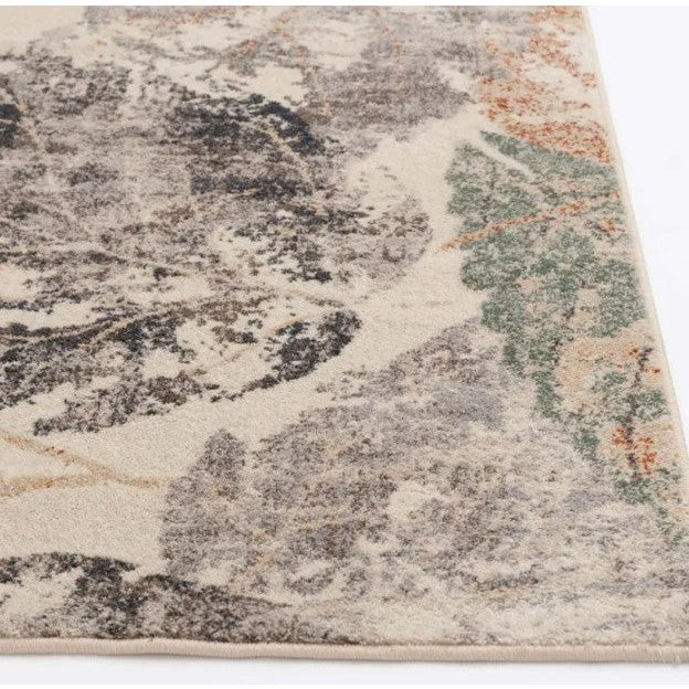 Corner of an abstract area rug with gray, green, and orange patterns on a cream background.