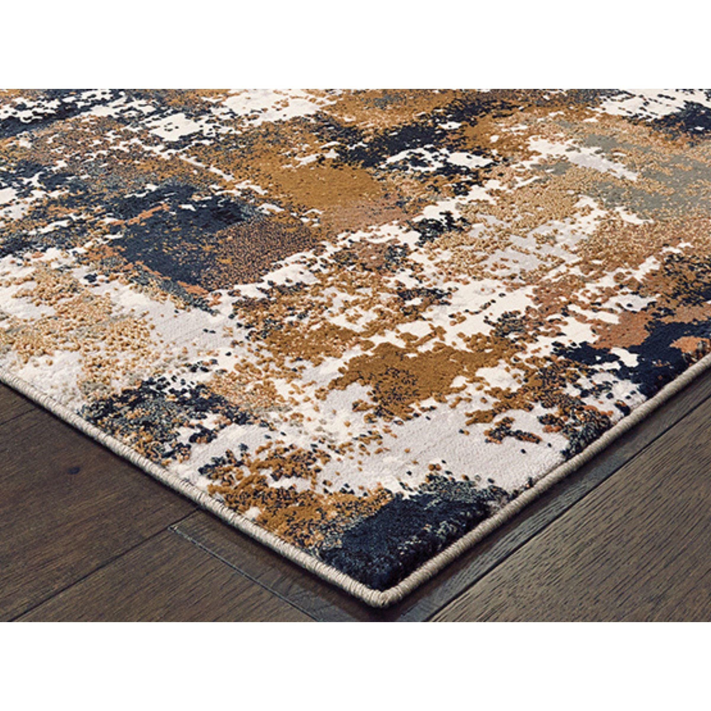 Corner of a modern area rug with an abstract pattern in brown, beige, and black on wood floor.