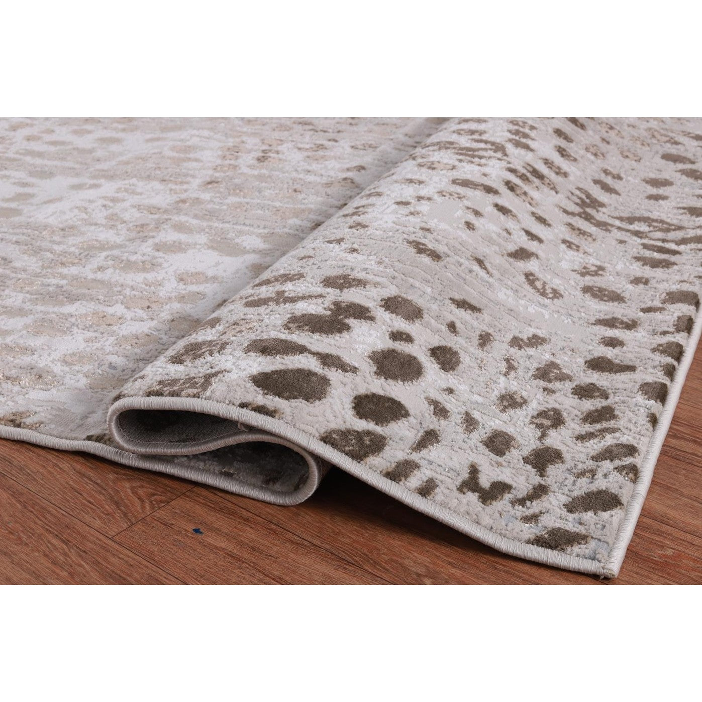 Beige and brown area rug with abstract spot pattern on hardwood floor.