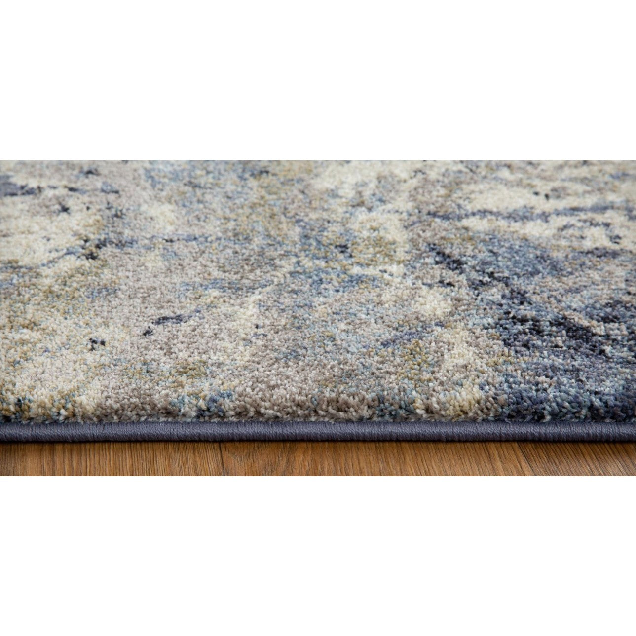 Close-up of a thick, multi-colored area rug edge on a wood floor.