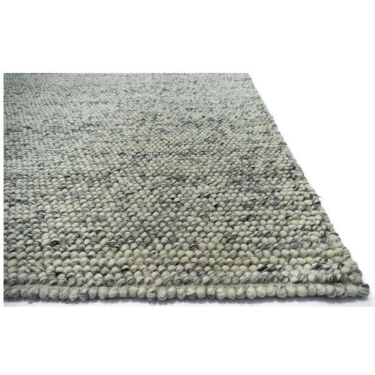 Close-up of textured grey woven rug corner.