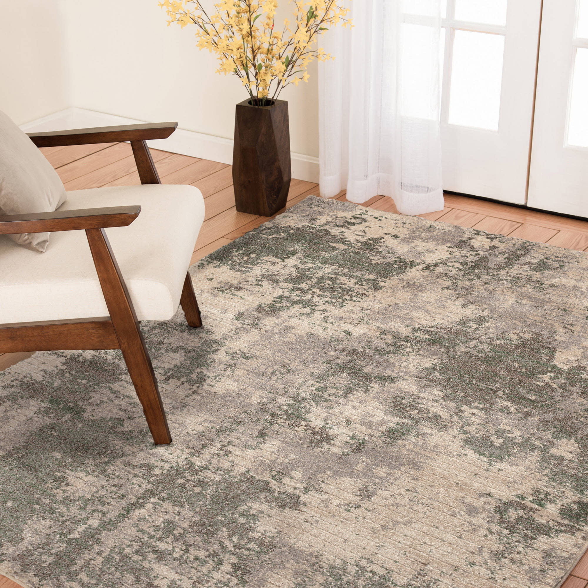 Modern living room with a neutral abstract area rug, a wooden chair, and a vase with yellow flowers.