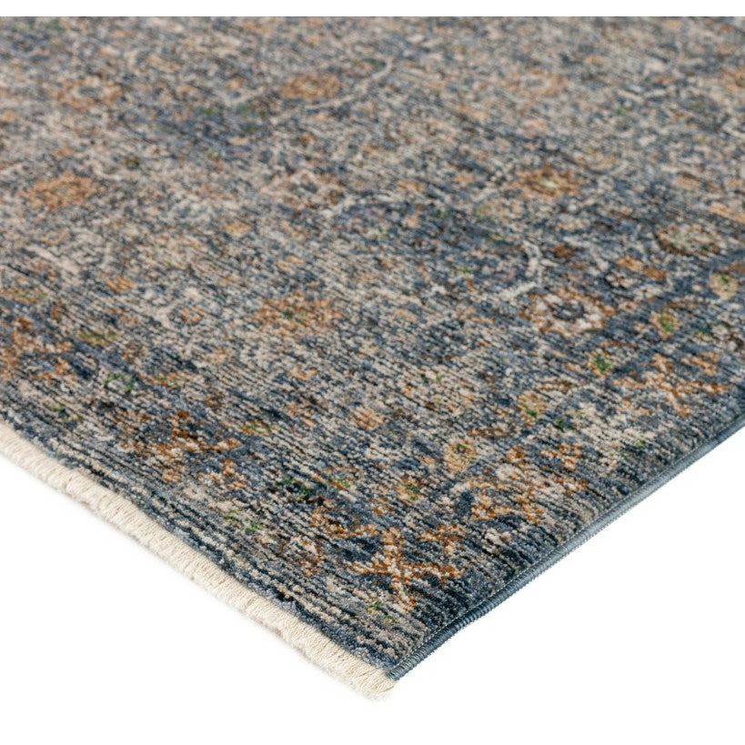 Corner of a blue and beige patterned area rug with low pile and subtle fringe.