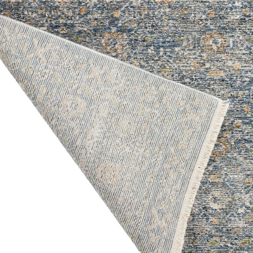 Corner of a blue patterned area rug flipped to show backing.