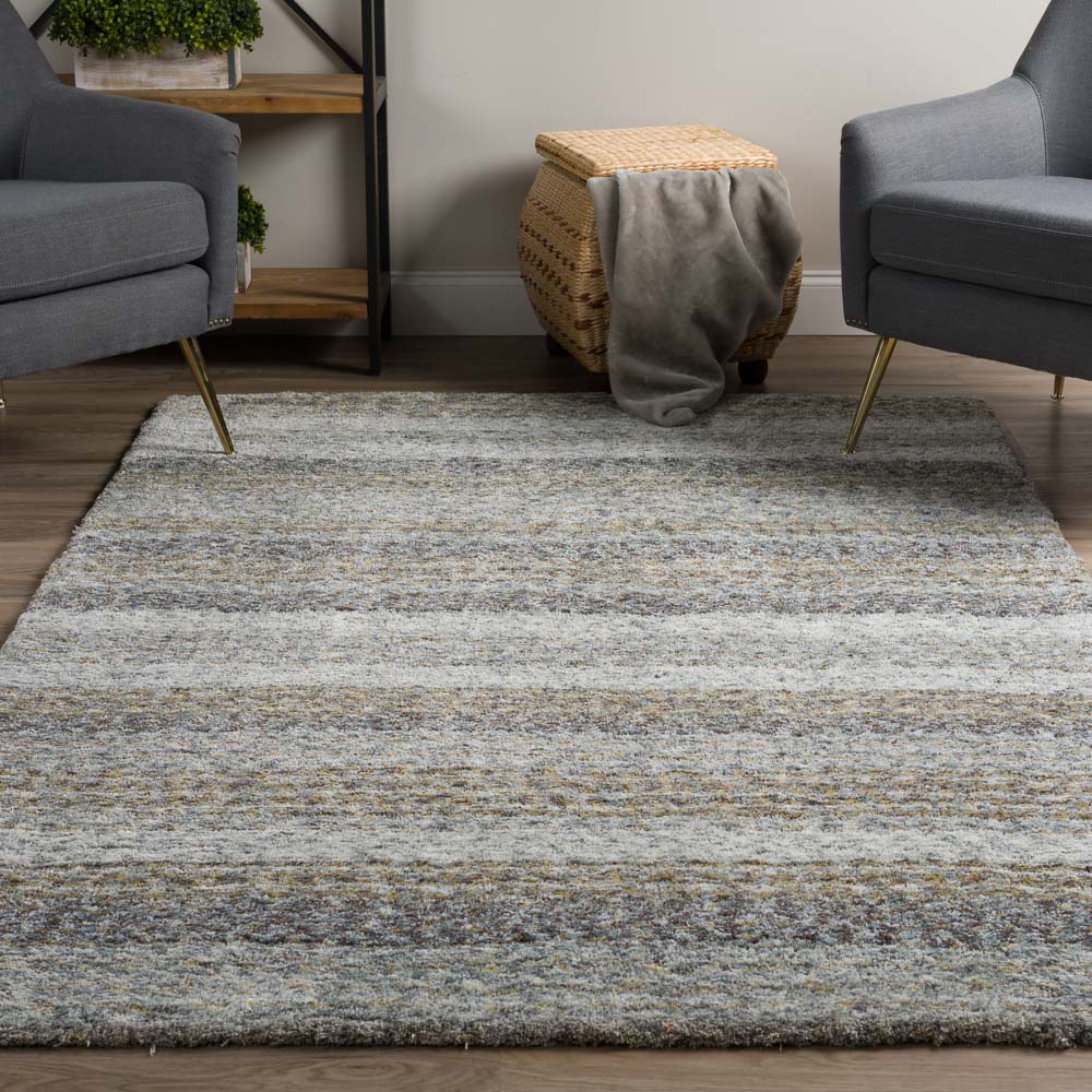 Gray and beige area rug in a modern living room with two chairs and a woven basket.