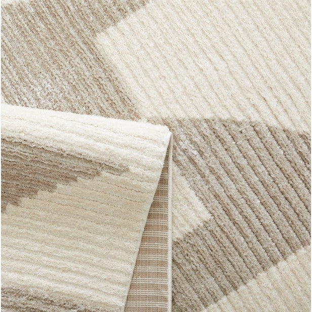 Beige and cream geometric area rug with visible textured pattern and folded corner.