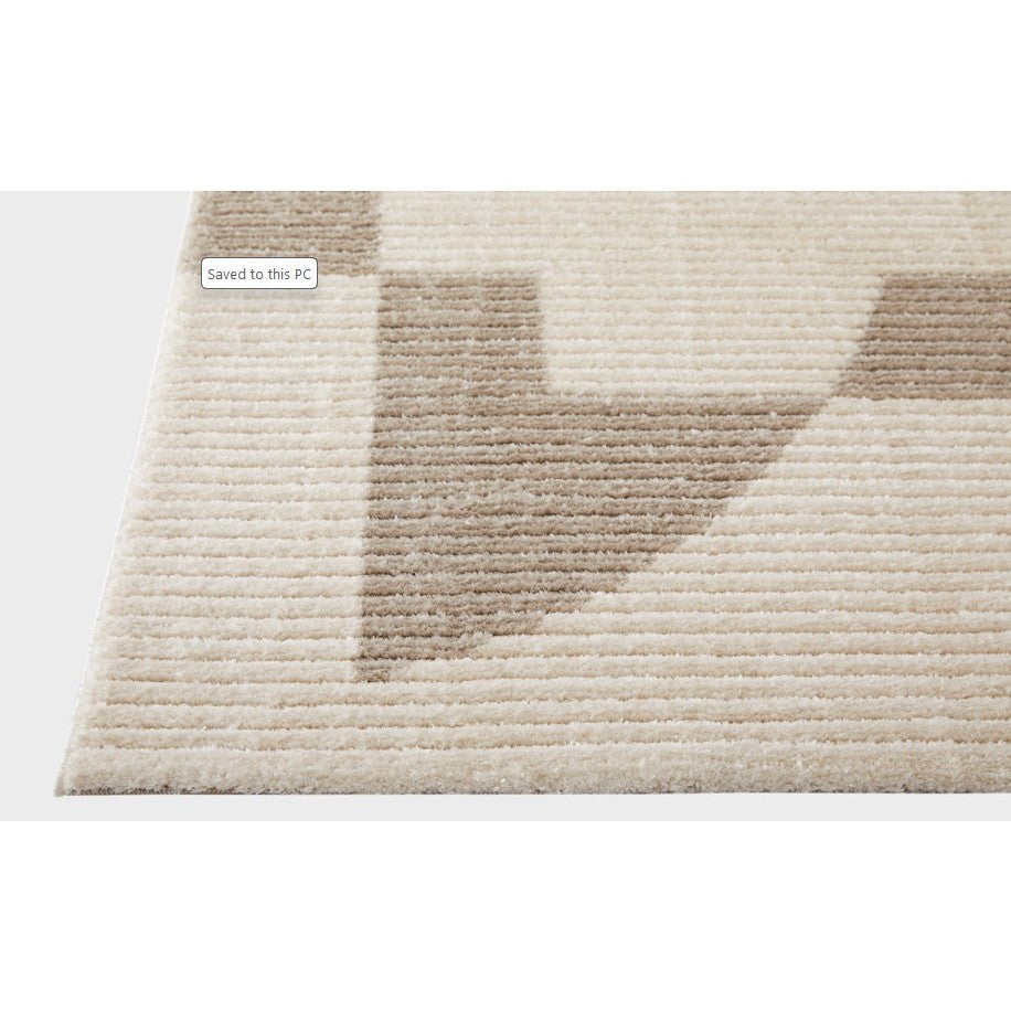 Close-up of a beige and tan geometric area rug corner, showing texture and pattern.