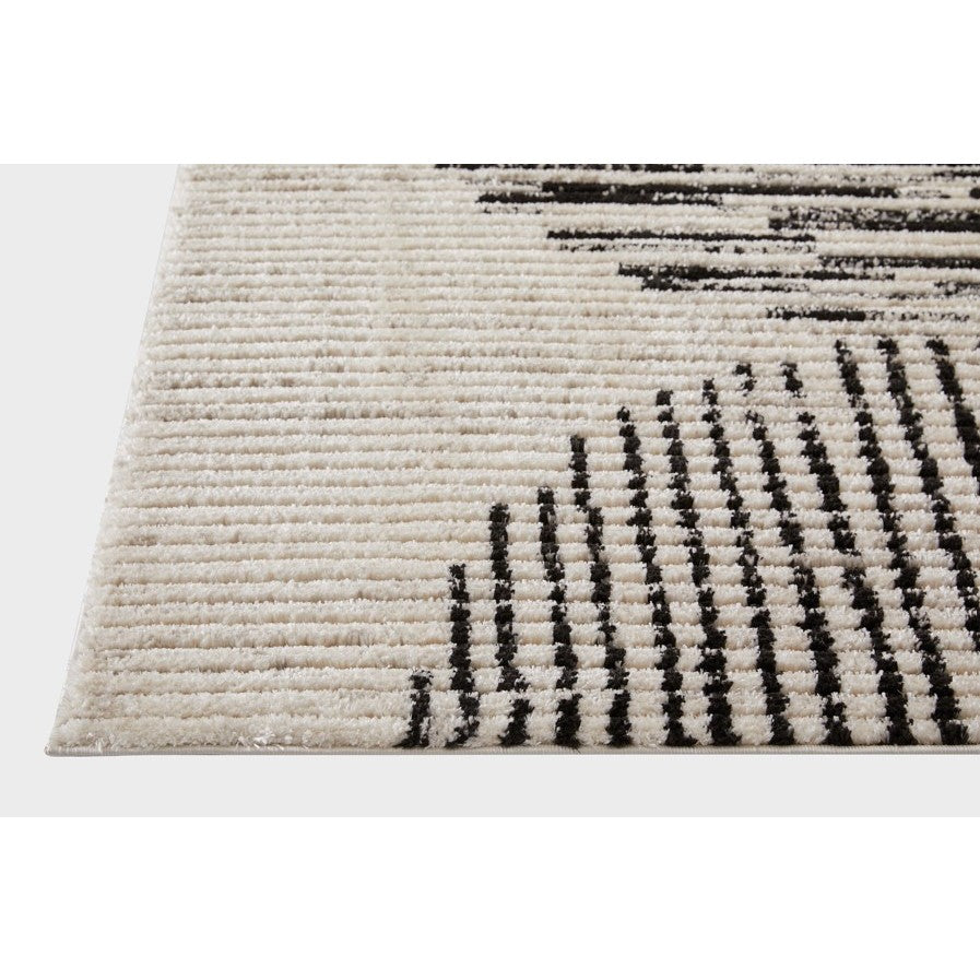 Corner of a cream rug with raised linear black pattern.