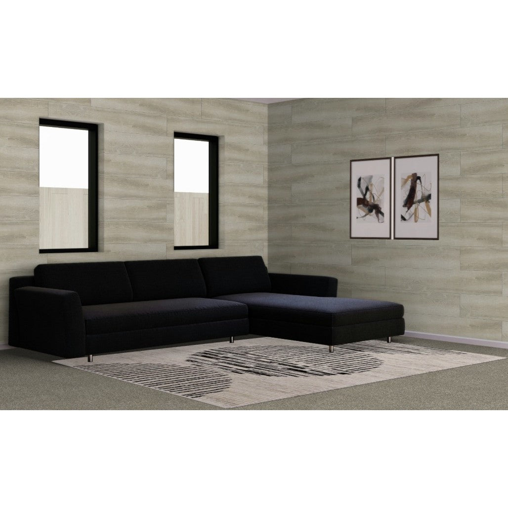 Modern black sectional sofa in a living room with light wood walls and abstract art.
