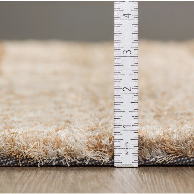 Side view of a beige rug with a ruler showing its pile height, measured in inches.