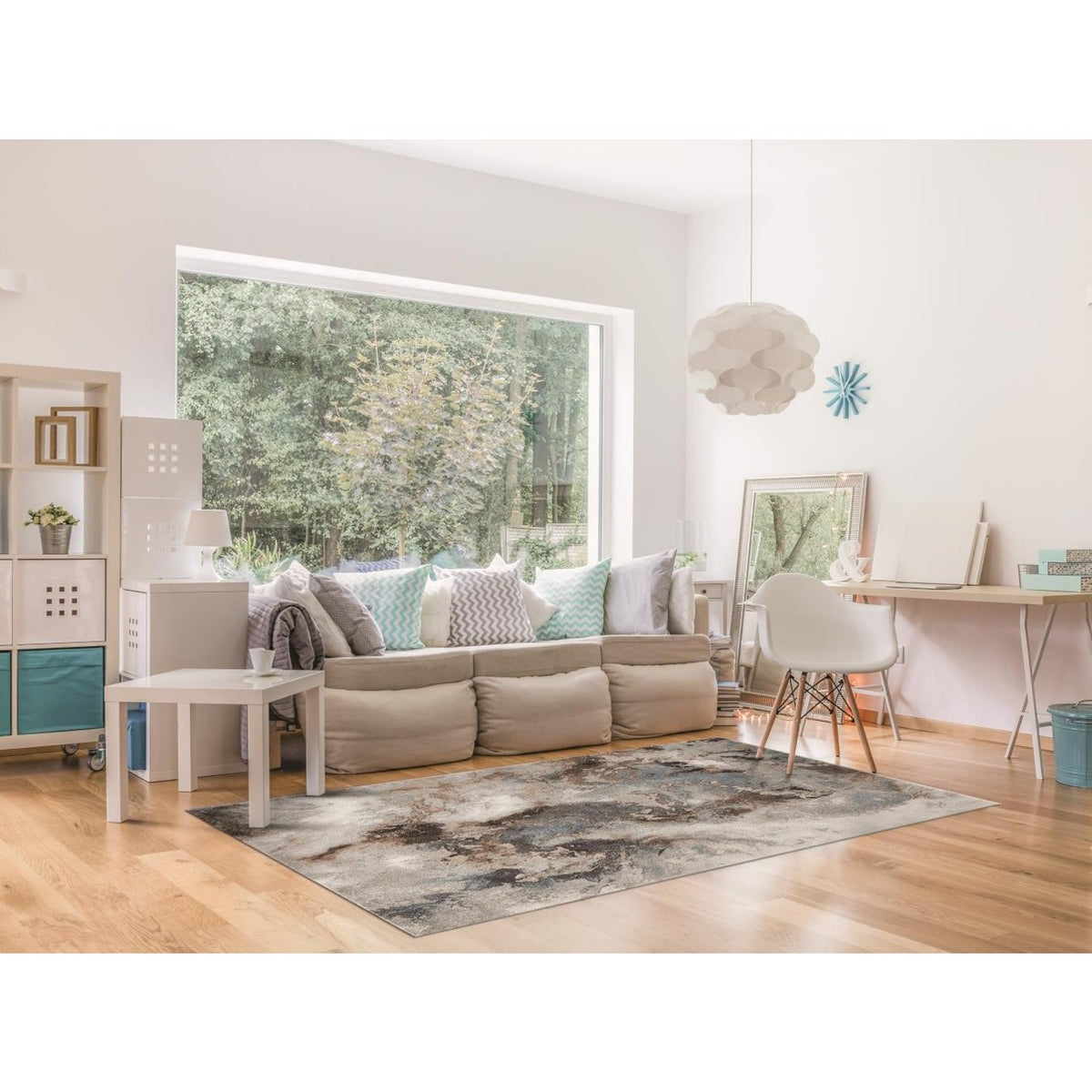 Modern living room with natural light, beige sofa, accent pillows, and abstract rug.