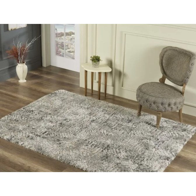 Gray area rug in a living space with chair and side table on wooden floor.
