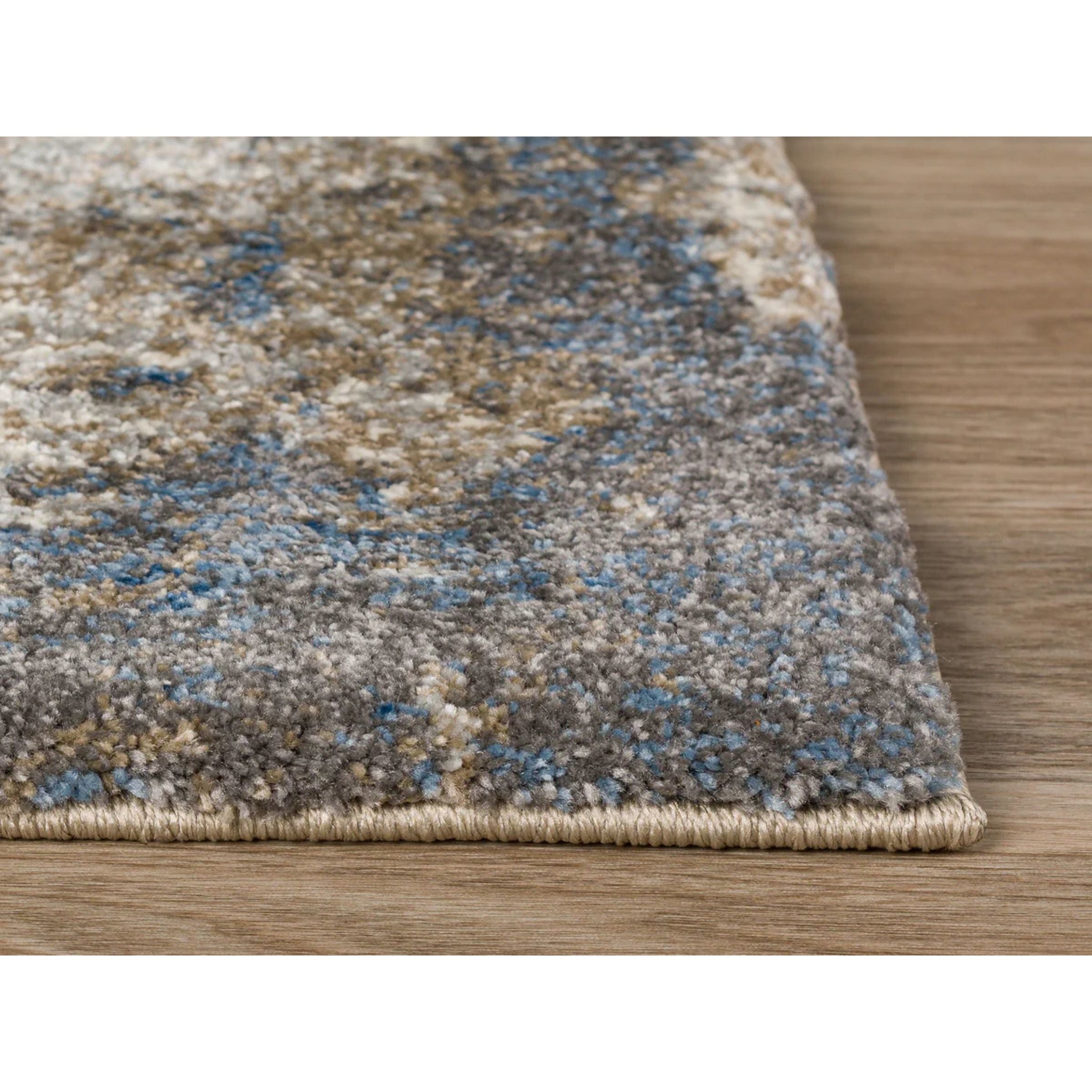 Close-up of multicolored area rug edge on wood floor.