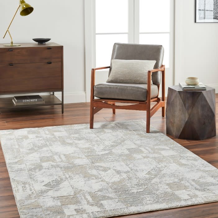 Contemporary living room with gray accent chair, wood side table, and patterned area rug.