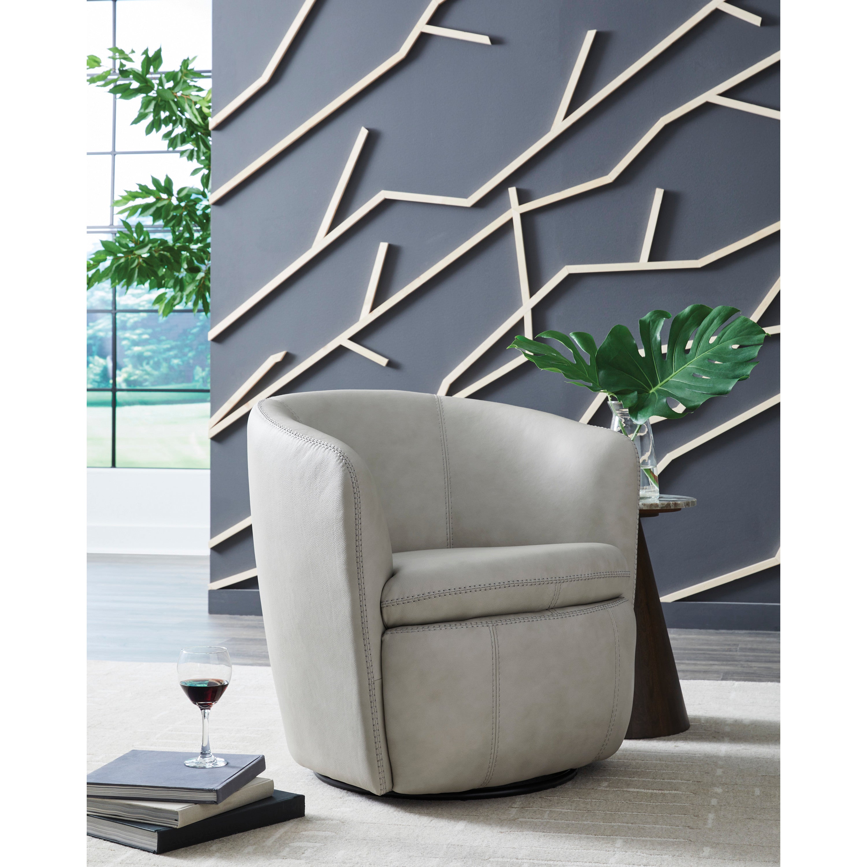 Modern gray swivel chair next to small table in a stylish room with geometric wall design.