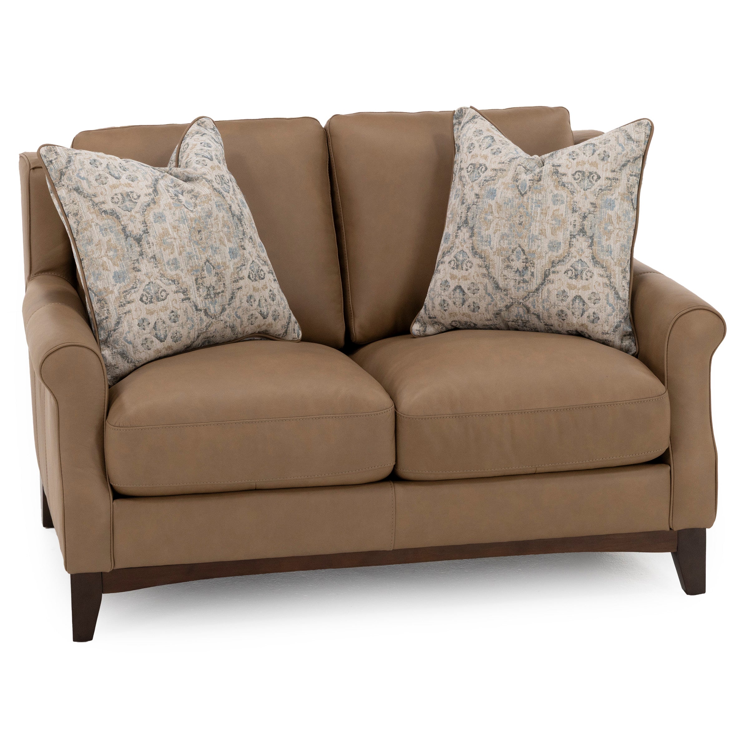 Tan leather loveseat with two patterned throw pillows.