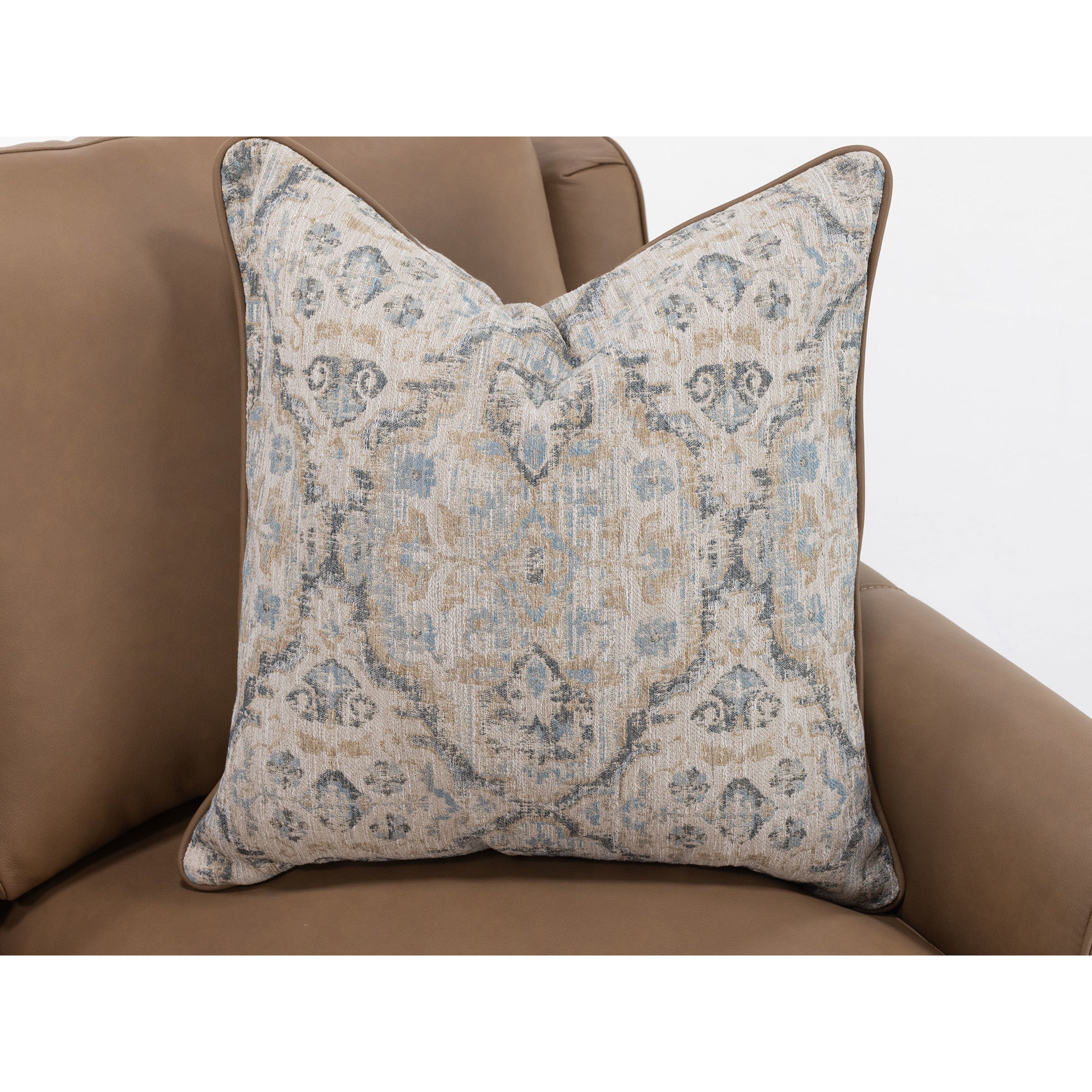 Decorative pillow with beige and blue pattern on a brown sofa.