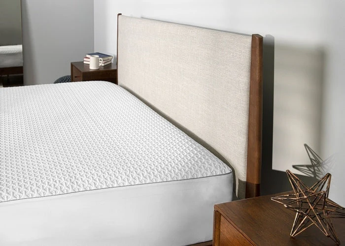White mattress on a bed with a wooden headboard in a bedroom setting.