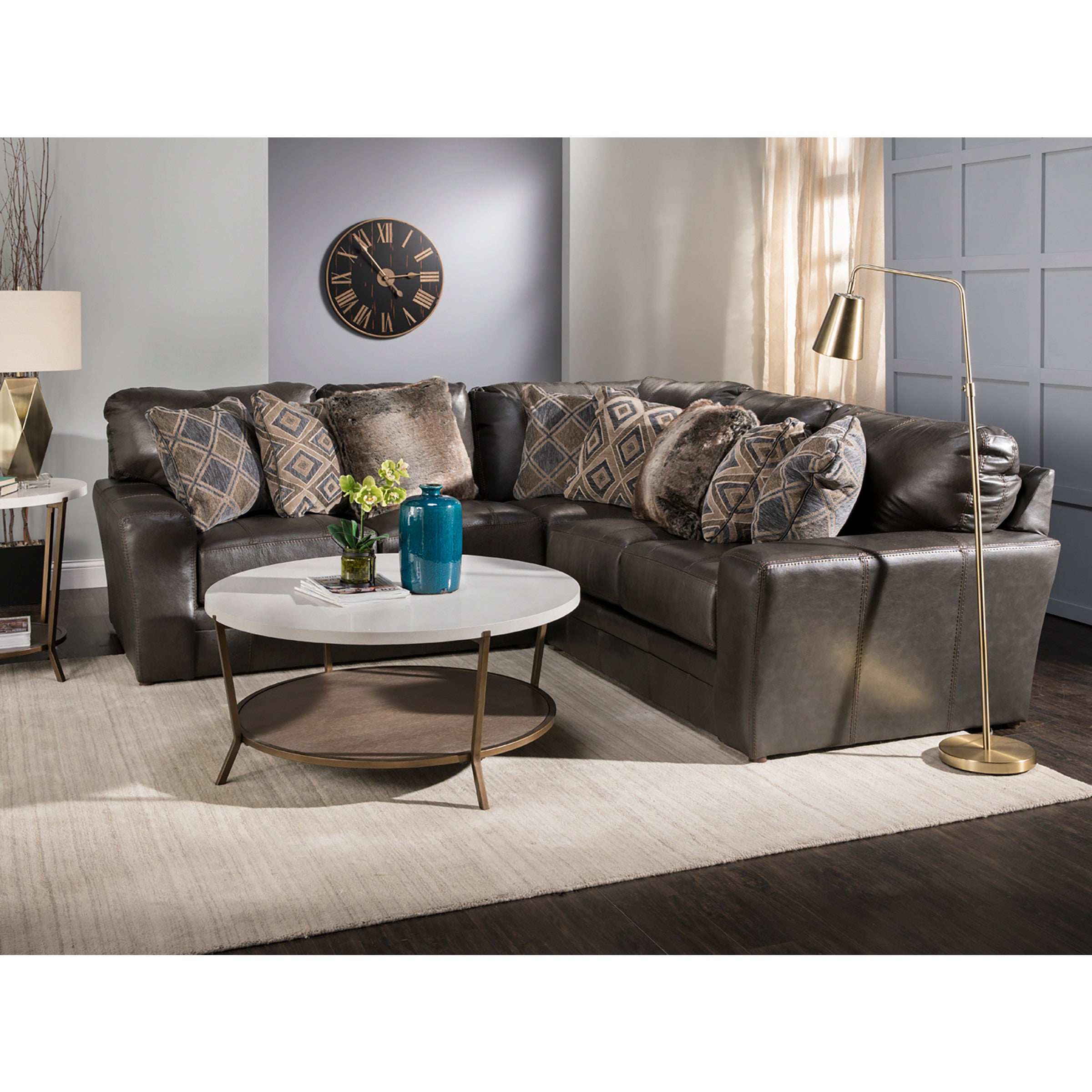 Modern living room with a dark sectional sofa, patterned pillows, and round coffee table.
