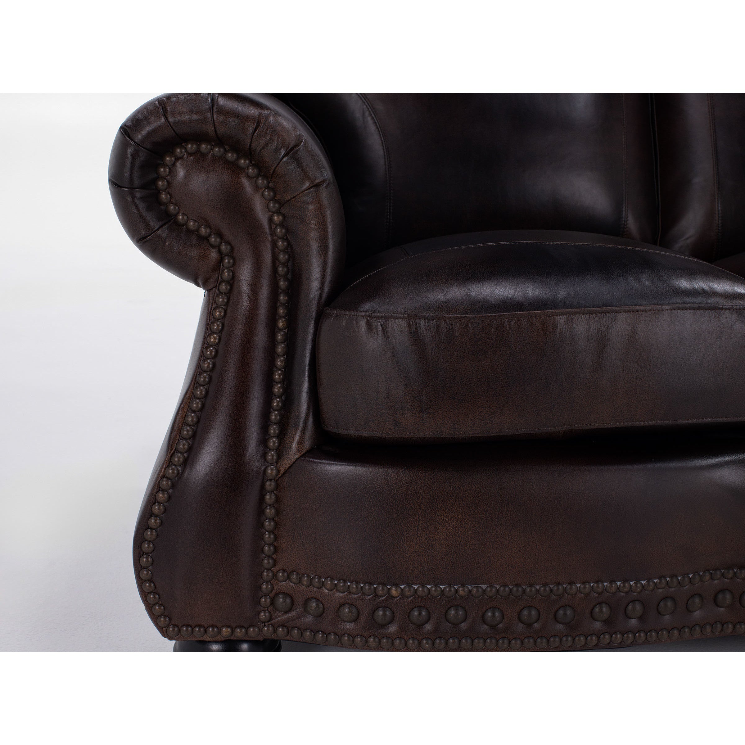 Close-up of a dark brown leather sofa arm with nailhead trim details.