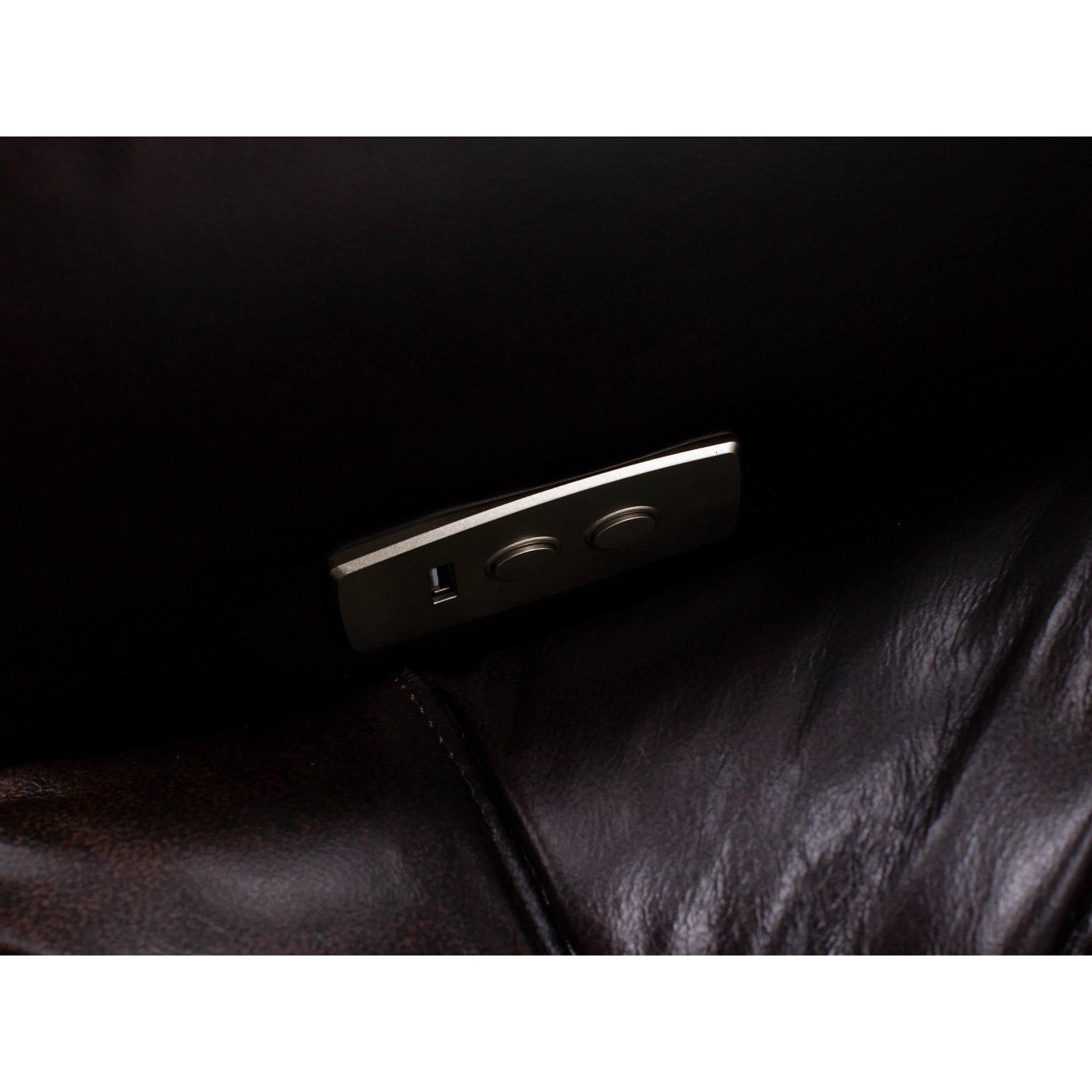 Close up of a leather recliner control panel with USB port and buttons for seat adjustment.