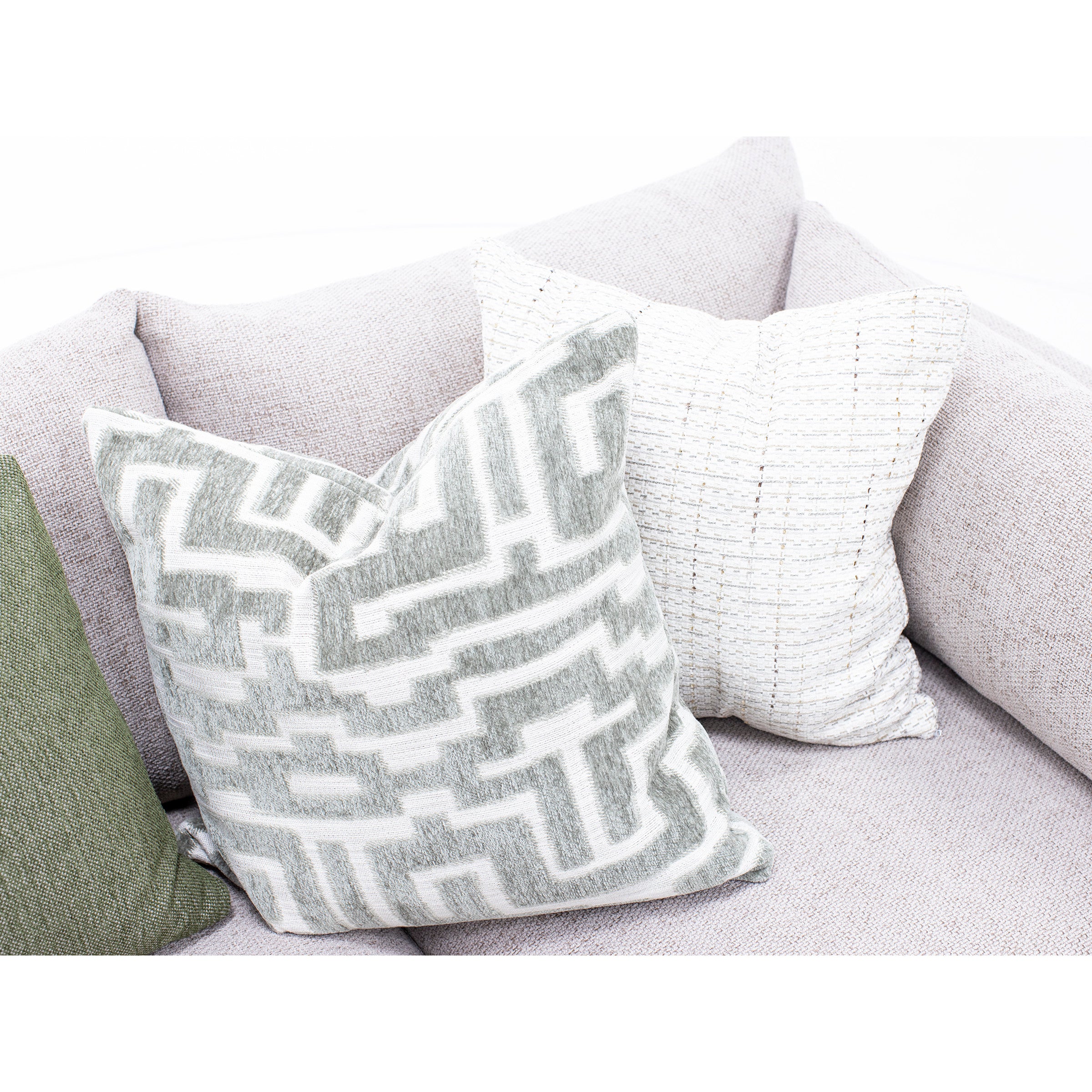 Three decorative accent pillows on a light fabric sofa.