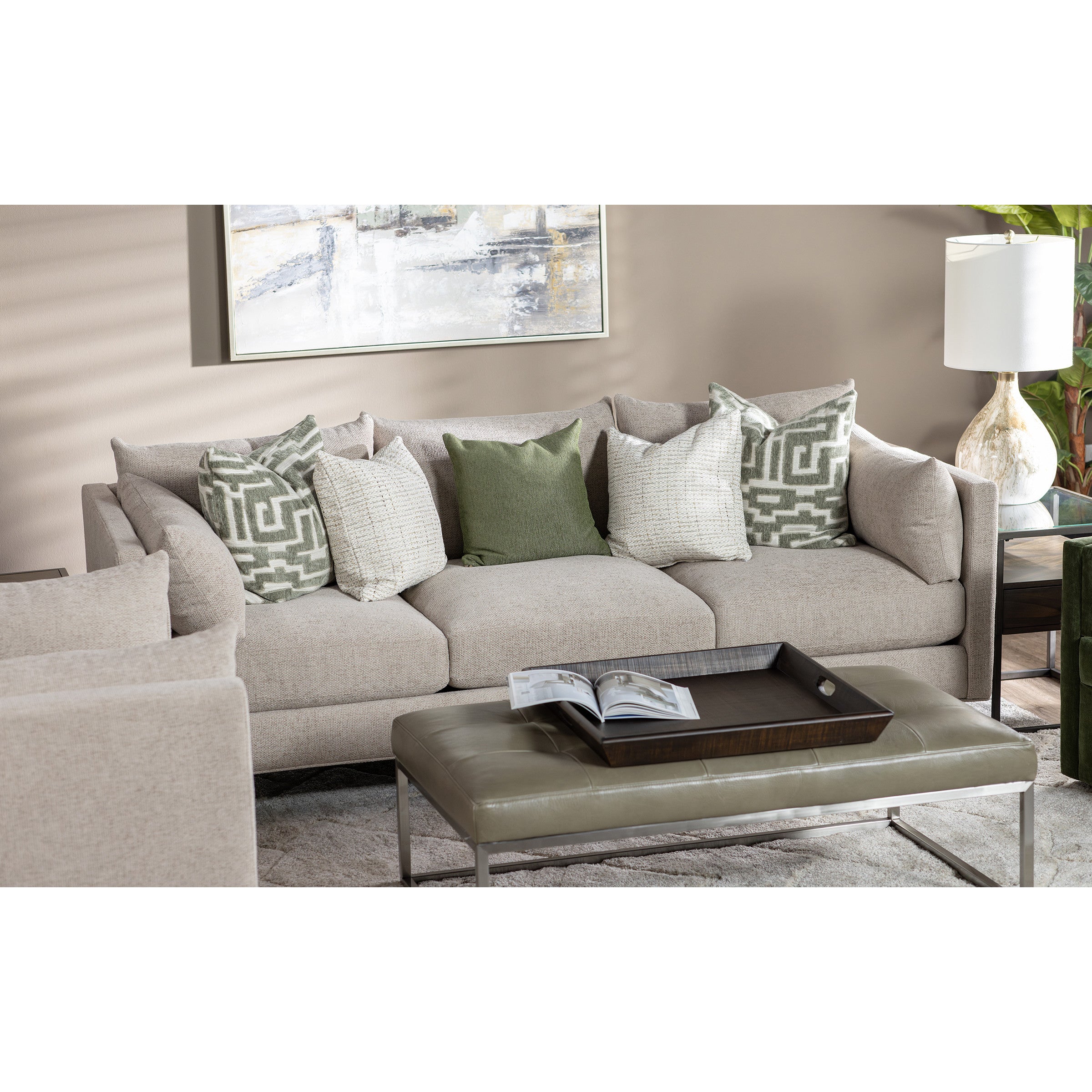 Beige sofa with green and cream pillows in a modern living room setting.